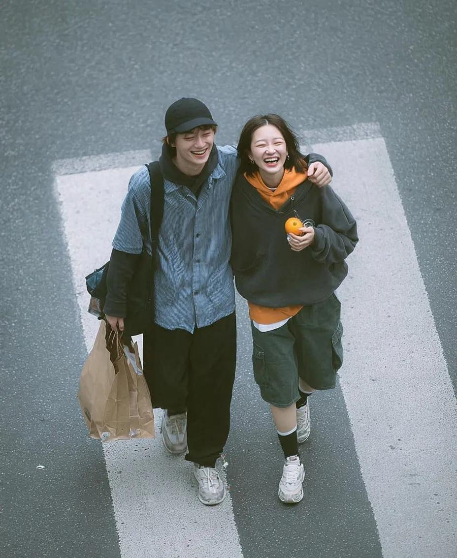 A cinematic overhead street photo of a young couple walking on a zebra crossing, candid and natural interaction, boy hap AI photo prompt example