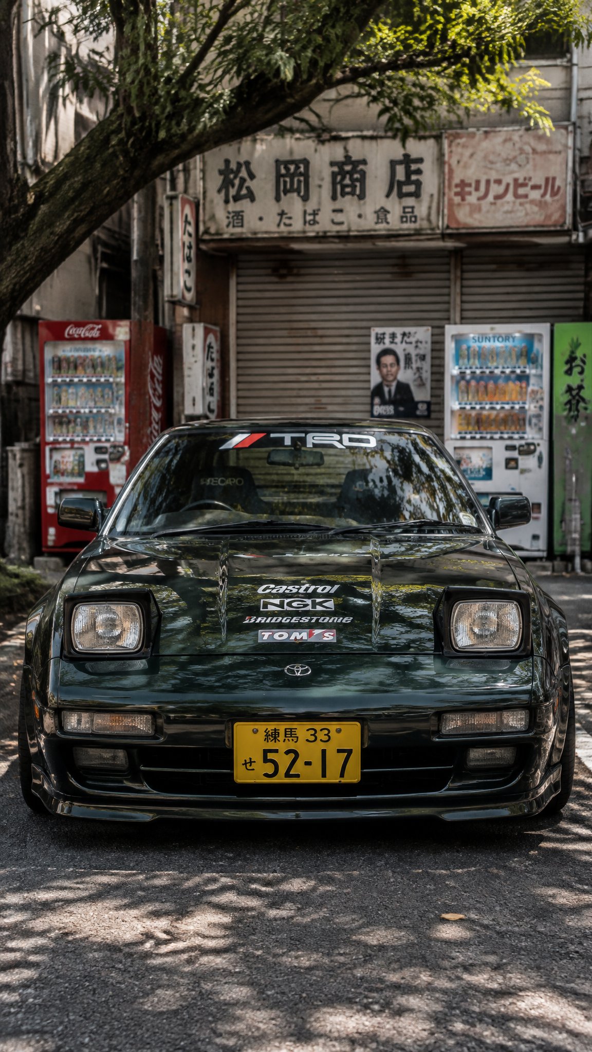 @Create image Front-view automotive street photography of a dark metallic forest-green classic 1980s Japanese sports car AI photo prompt example